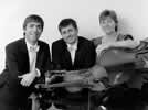 Black & white image of the trio sitting with their stringed instruments