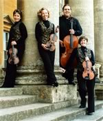 Lochrian Ensemble standing against a stone pillar holding their stringed instruments