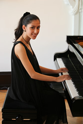 Mishka Rushdie Momen sitting at a piano