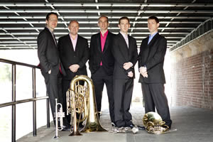 Onxy Brass standing with their instruments under a bridge