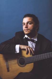 Emanuele Addis seated with his guitar