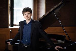 Antoine Préat standing in front of a piano