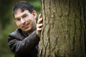 Duncan Honeybourne standing alongside and holding the trunk of a tree