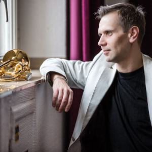 Cyrill Gussaroff leaning on a deep window-sill, where his trumpet is located