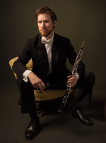 Owen Dennis sitting whilst holding his oboe.